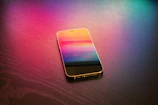 Close-up of a sleek smartphone with vibrant screen colors on a wooden table.