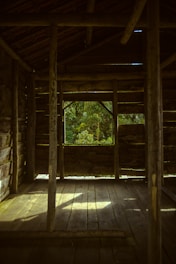 Close-up of hands cleaning a wooden cabin floor with natural light streaming in.