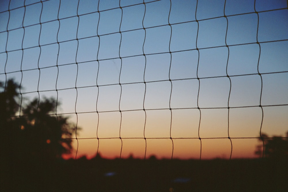 Silhouette d’une clôture à mailles de chaîne au coucher du soleil
