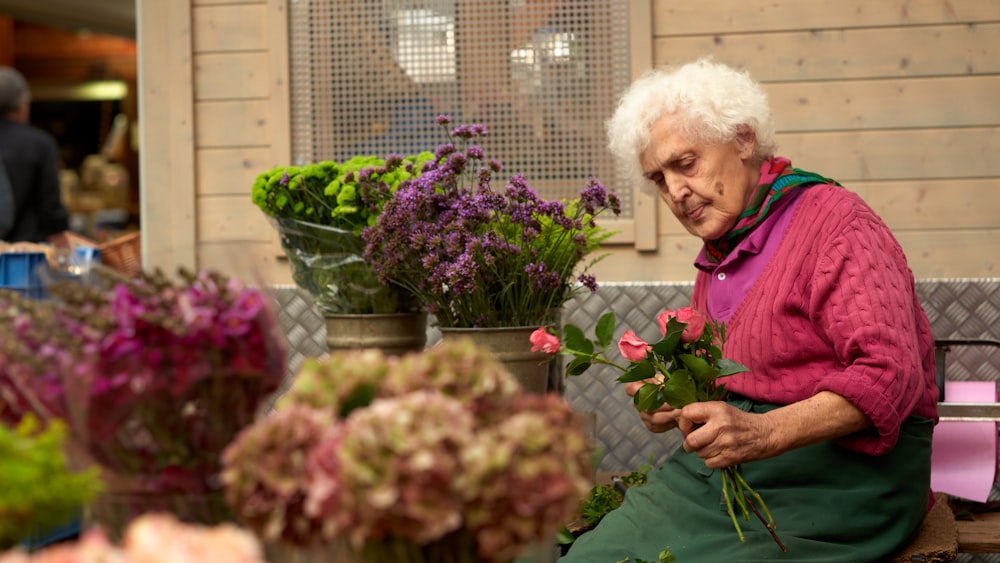 Mujer con chaqueta púrpura de pie junto a las flores