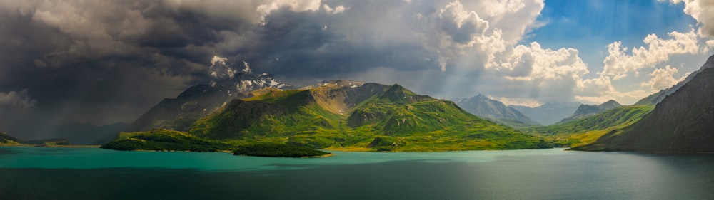 green mountains near body of water under cloudy sky during daytime