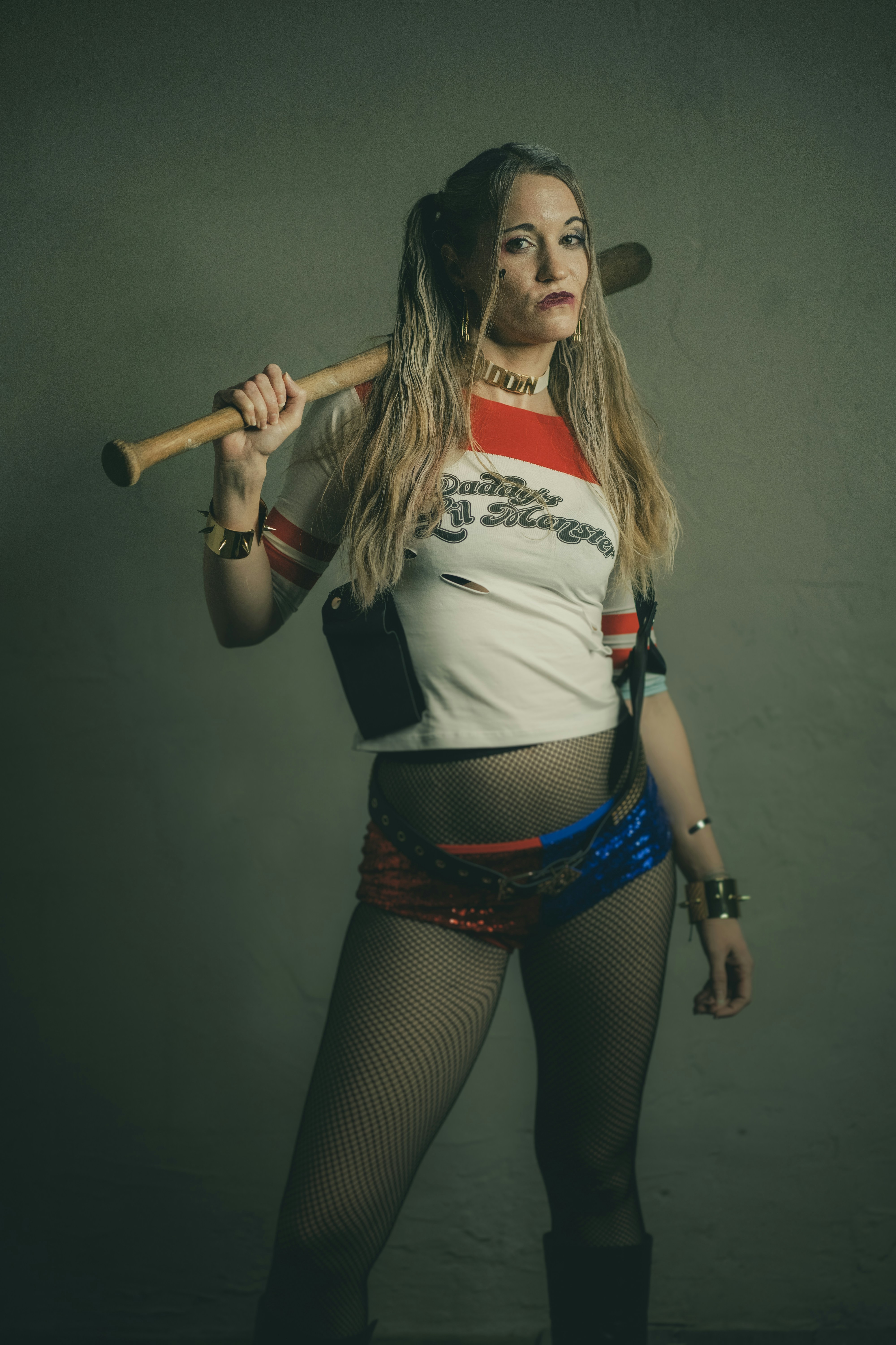 Wanita dengan crop top putih dan merah dan celana pendek denim biru memegang tongkat kayu coklat