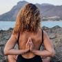 woman in black bikini sitting on rock near sea during daytime