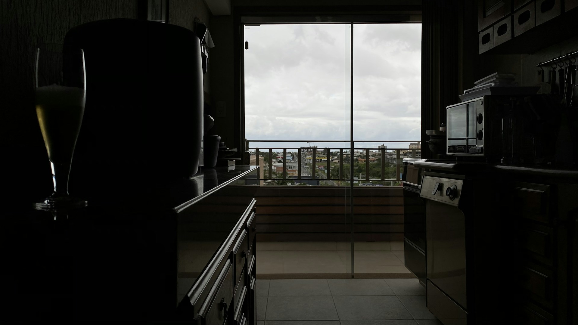 A sleek apartment kitchen with clean lines, stainless steel appliances, and a view of the city's skyline from the balcony.