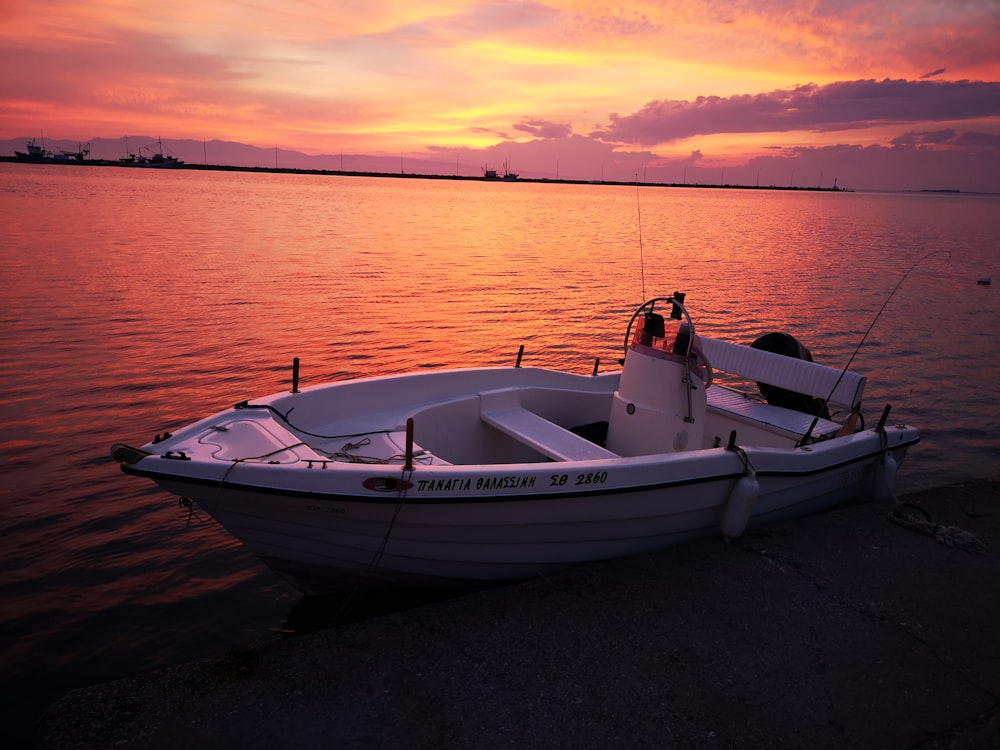 man in white shirt sitting on white boat on sea during sunset