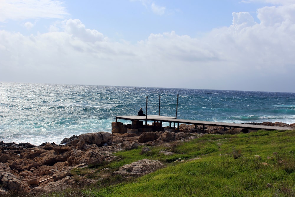 brown wooden bench on brown rock near body of water during daytime