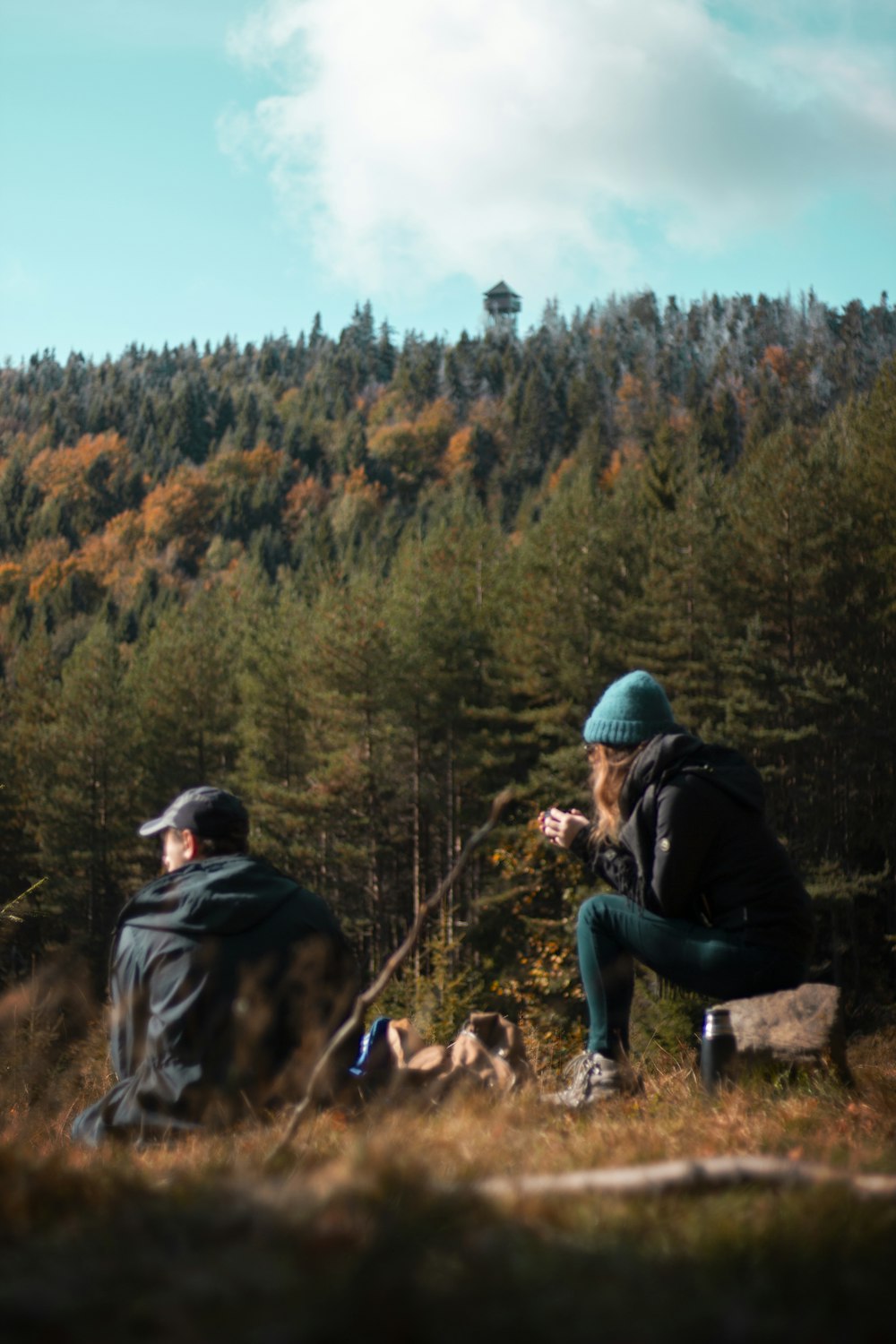 man in black jacket sitting on rock beside woman in black jacket