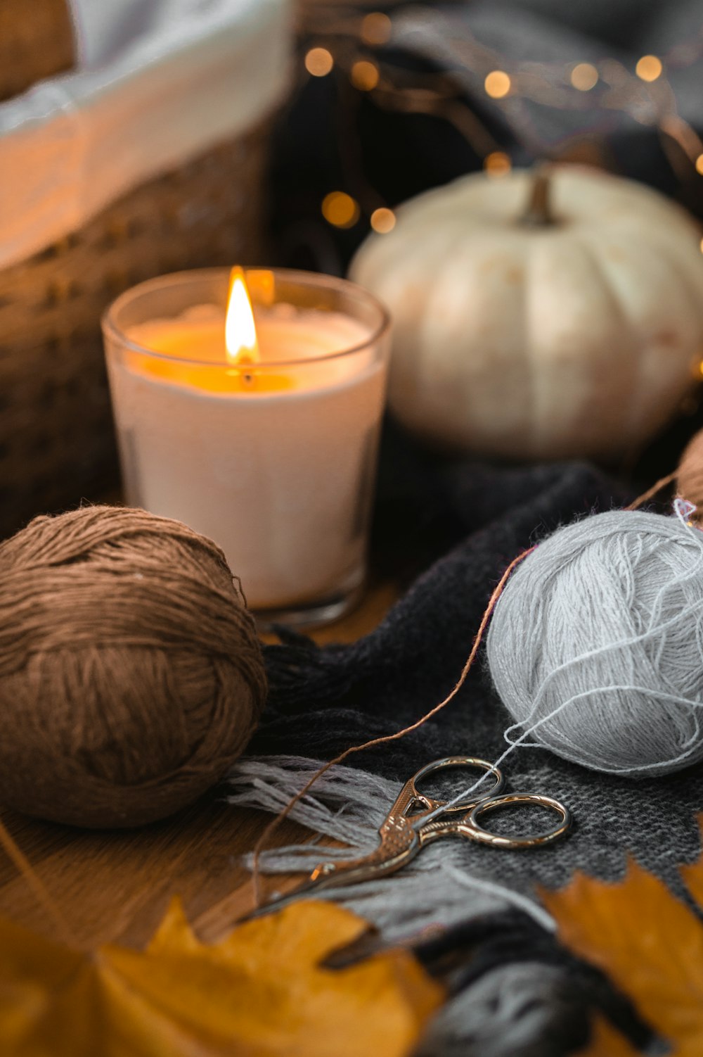 white candle beside brown yarn and gray yarn