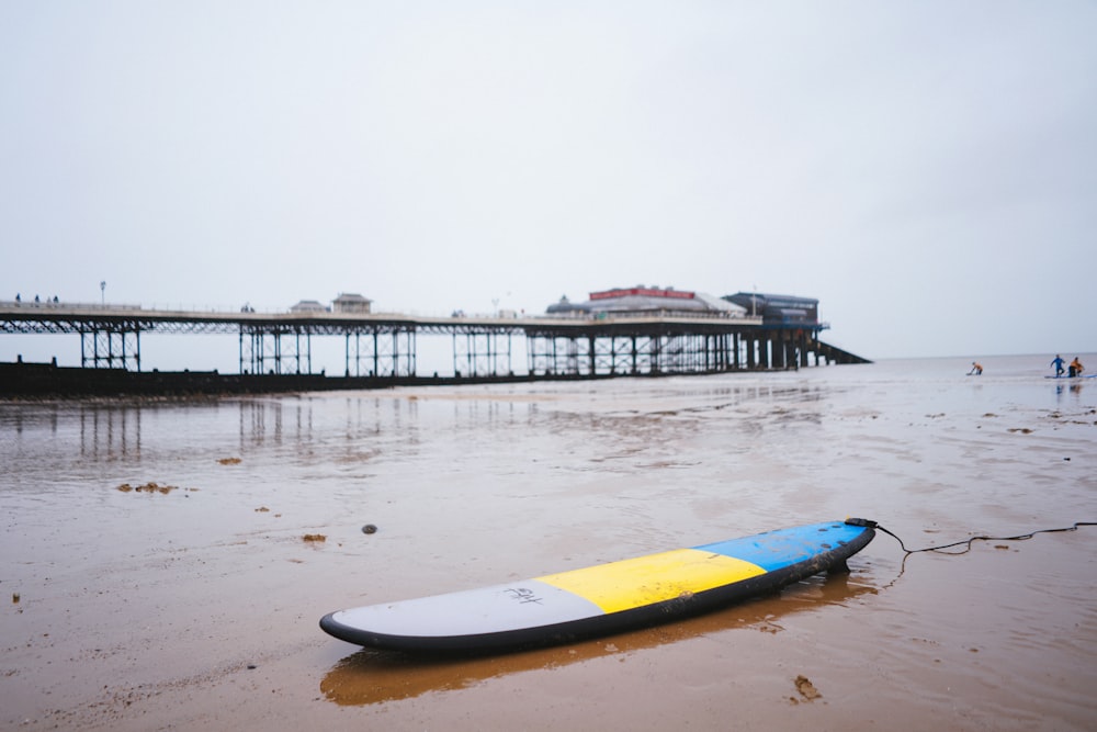 Tabla de surf azul y amarilla en la playa durante el día