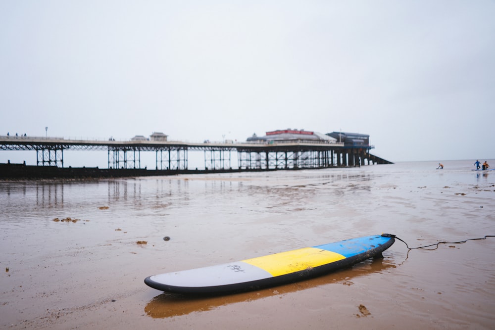 blue and yellow surfboard on beach during daytime