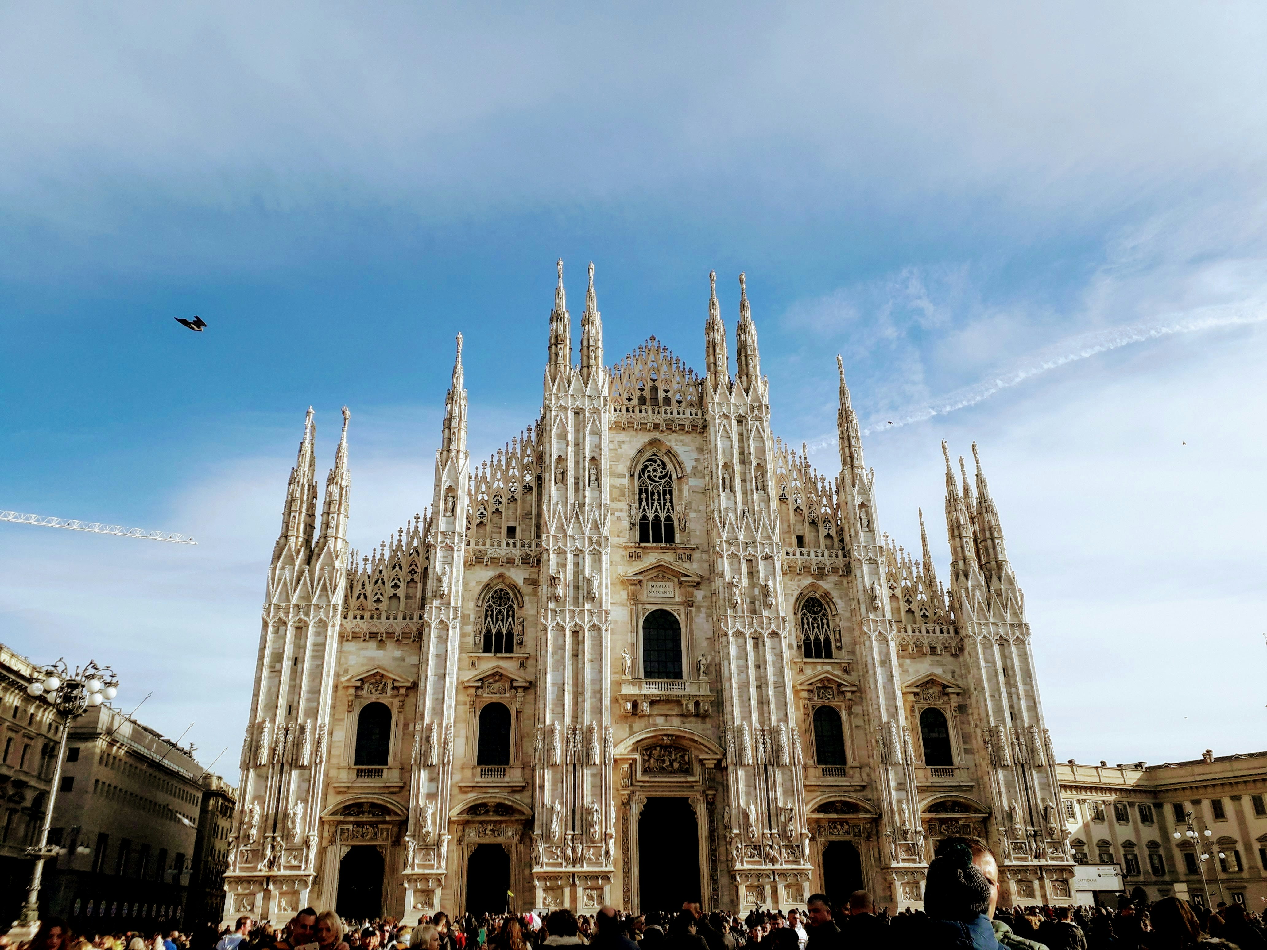 Persone che camminano vicino a un edificio di cemento bianco durante il giorno