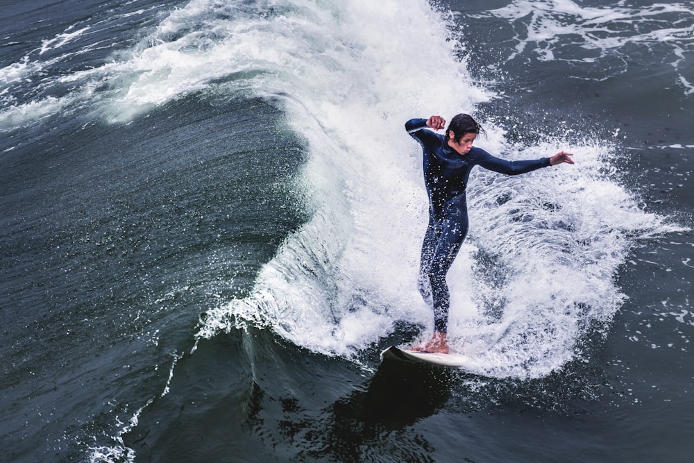 man in black wetsuit surfing on sea waves during daytime