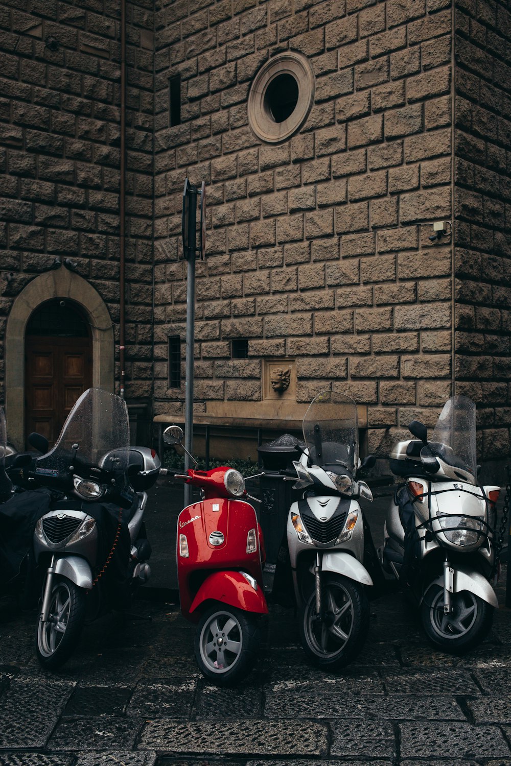 red and black motorcycle parked beside brown brick wall