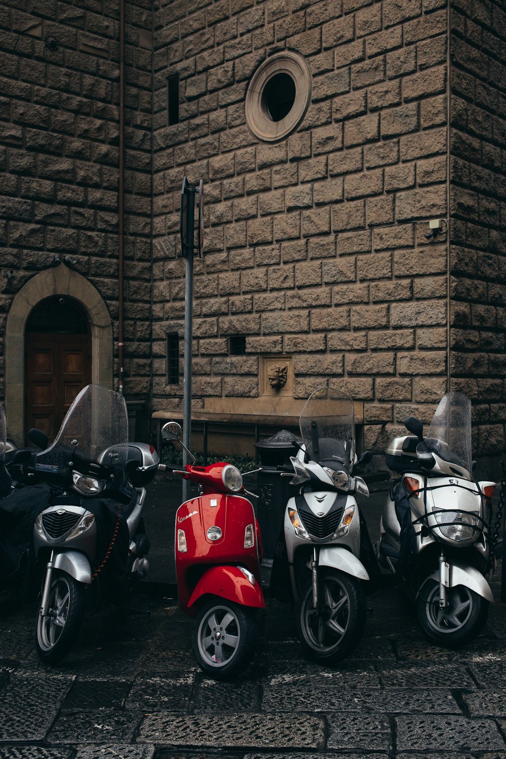 Moto rossa e nera parcheggiata accanto al muro di mattoni marroni