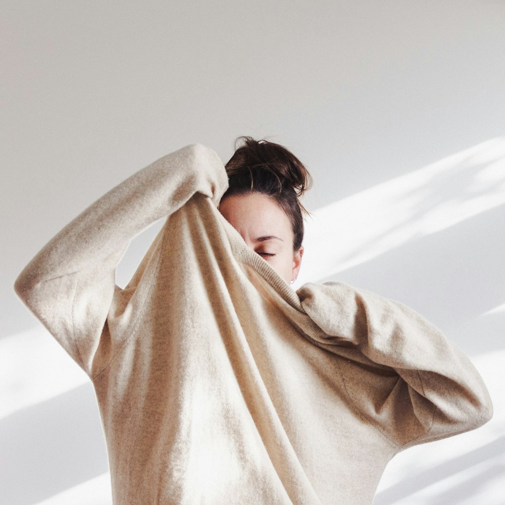 woman in white long sleeve shirt covering her face with brown scarf