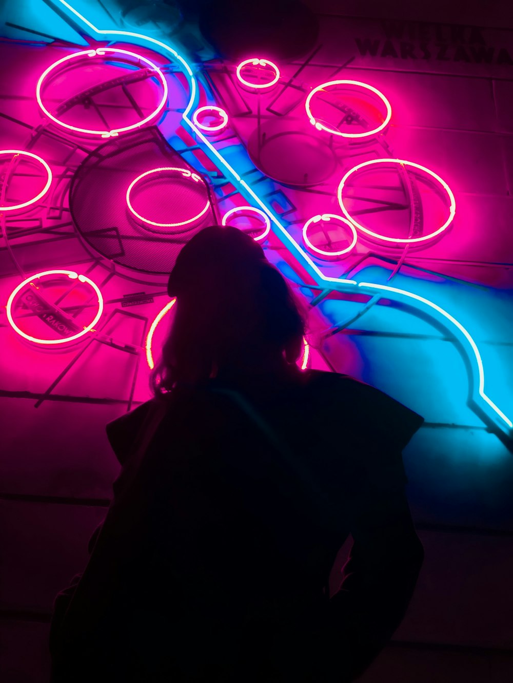 woman in black jacket standing in front of neon light signage