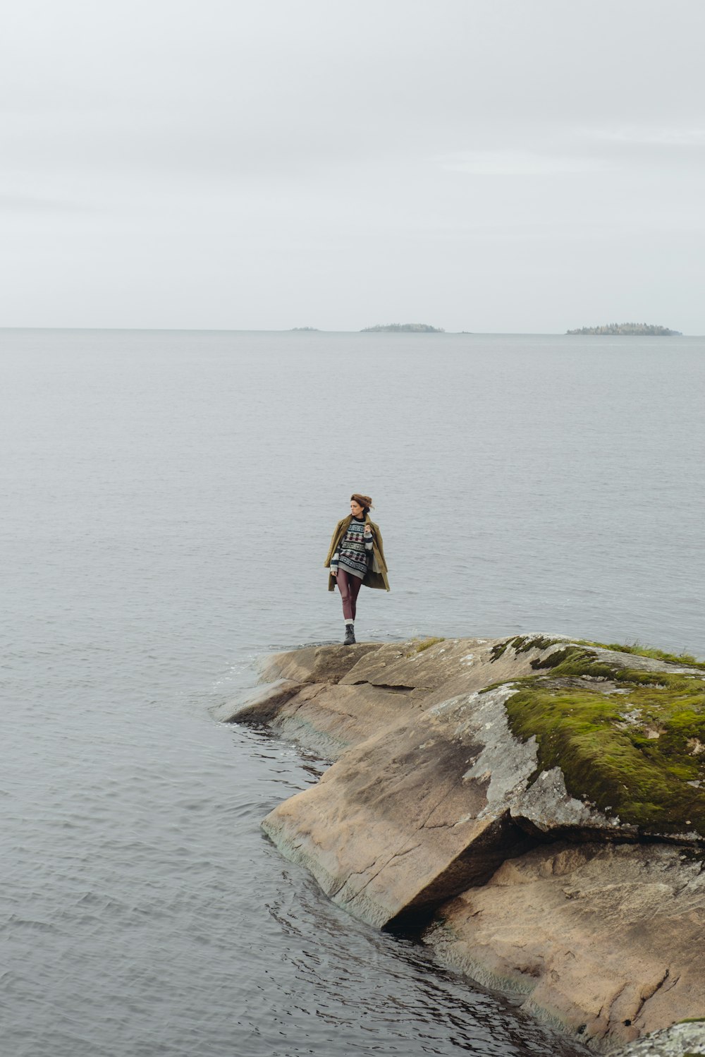 woman in red shirt standing on brown rock formation near body of water during daytime