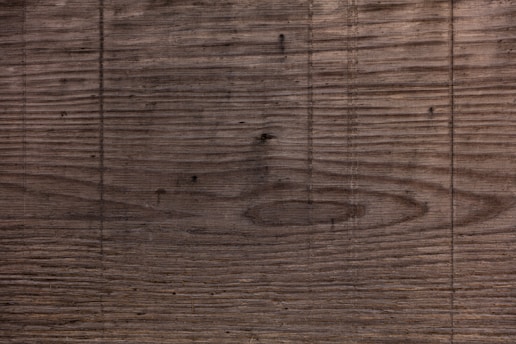 Weathered wooden surface with distinct grain patterns and subtle variations in color.