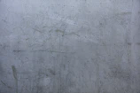 Close-up of a textured concrete wall with subtle urban scratches and faded paint.