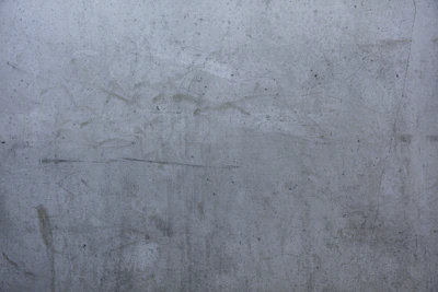 Close-up of a textured concrete wall with subtle urban scratches and faded paint.