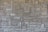 A textured, interlocking pattern of rectangular stone bricks in varying shades of beige and gray, creating a rustic and sturdy appearance.