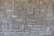 A textured, interlocking pattern of rectangular stone bricks in varying shades of beige and gray, creating a rustic and sturdy appearance.
