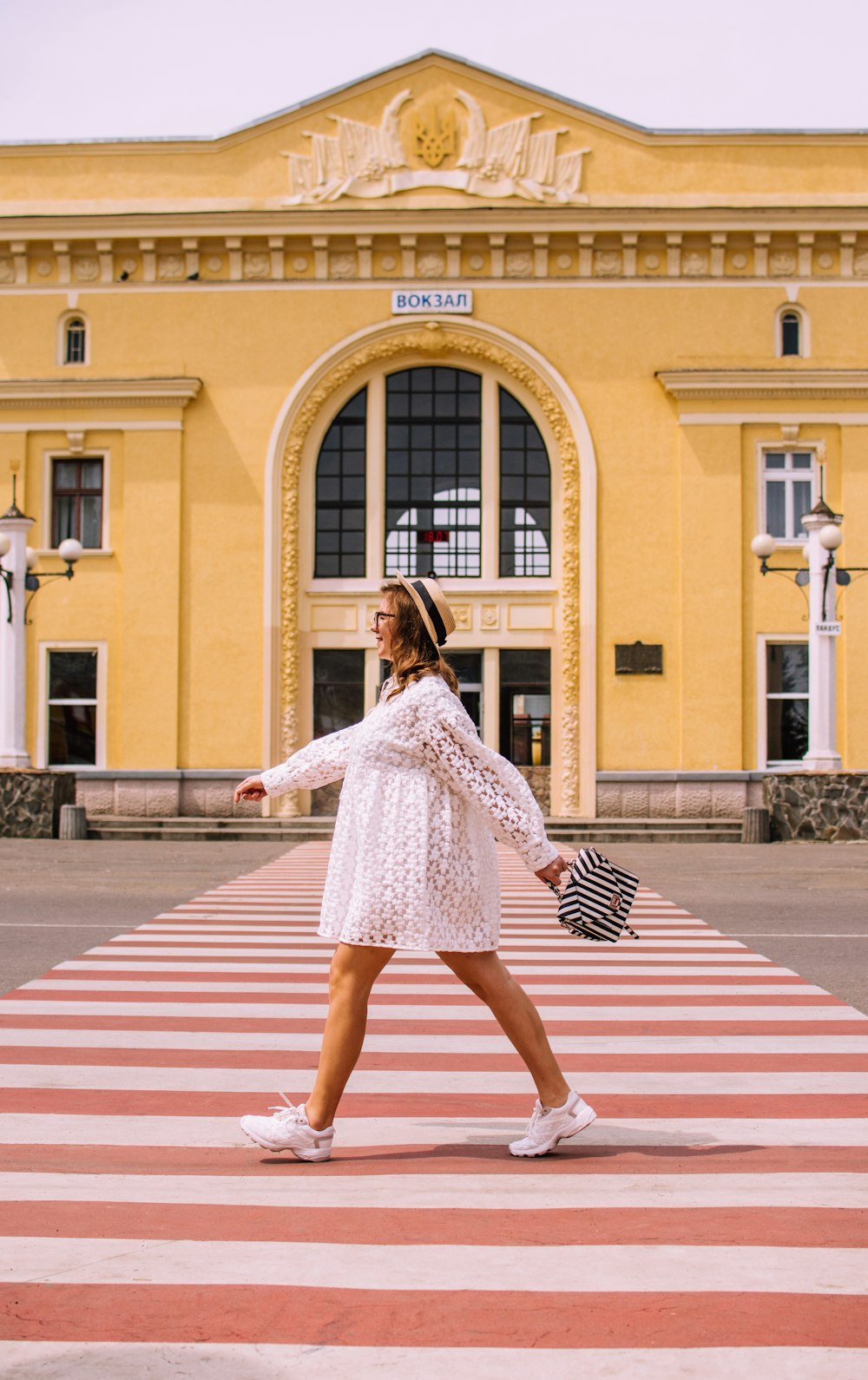 woman in white long sleeve dress walking on pedestrian lane during daytime