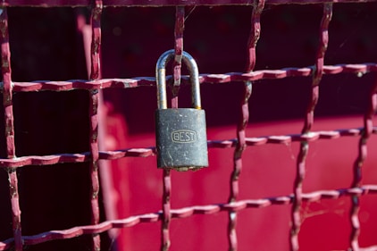 brass padlock on red metal fence