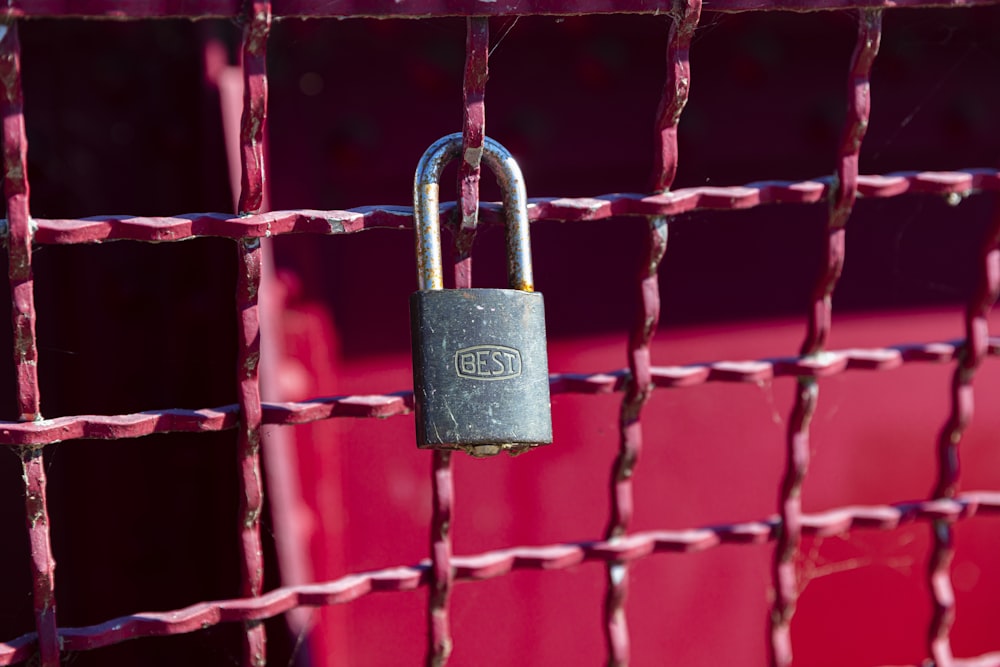 brass padlock on red metal fence