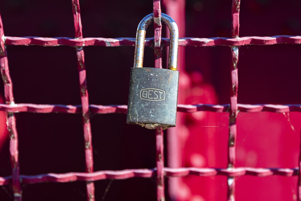 brass padlock on red metal fence