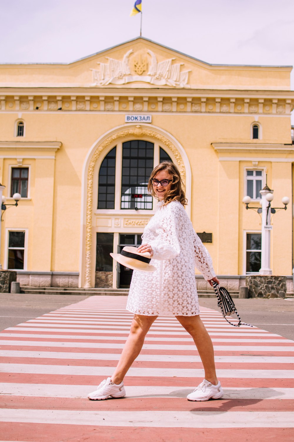 a woman walking across a cross walk in front of a building