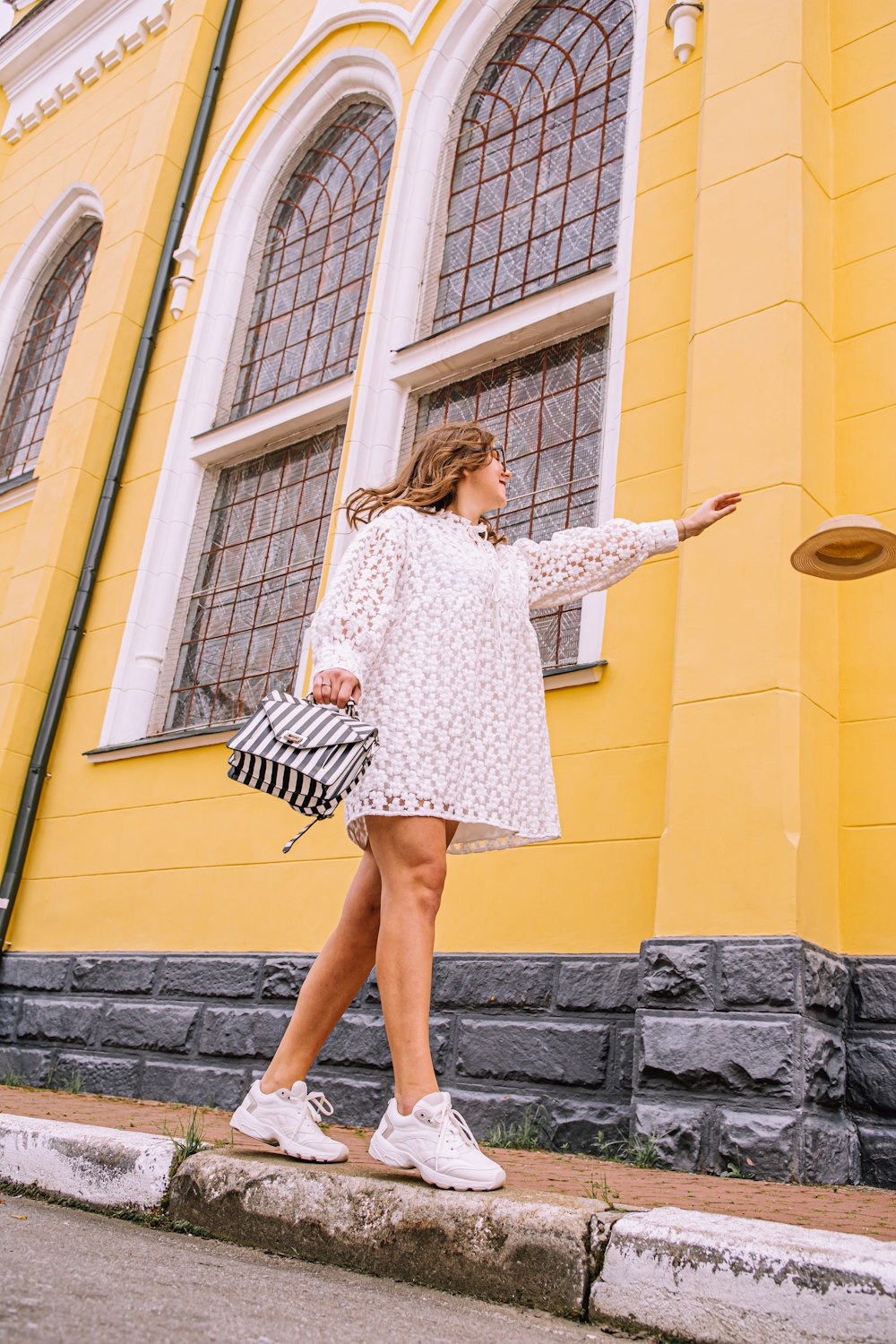 woman in white and black long sleeve dress standing on gray concrete wall during daytime