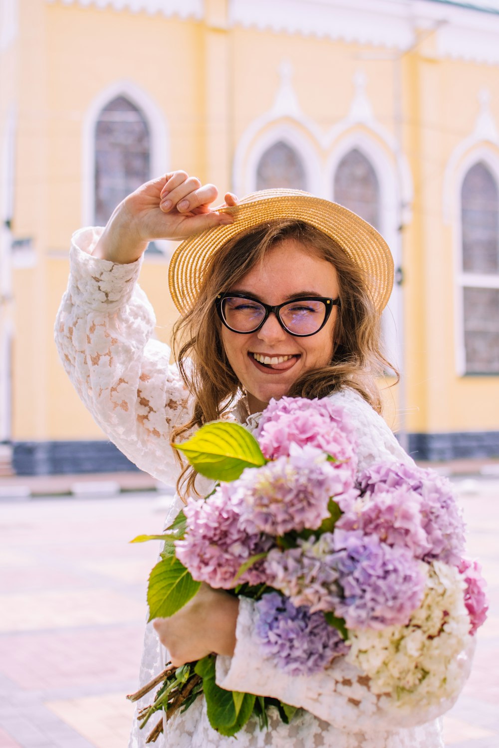 woman in white long sleeve shirt holding pink flower bouquet