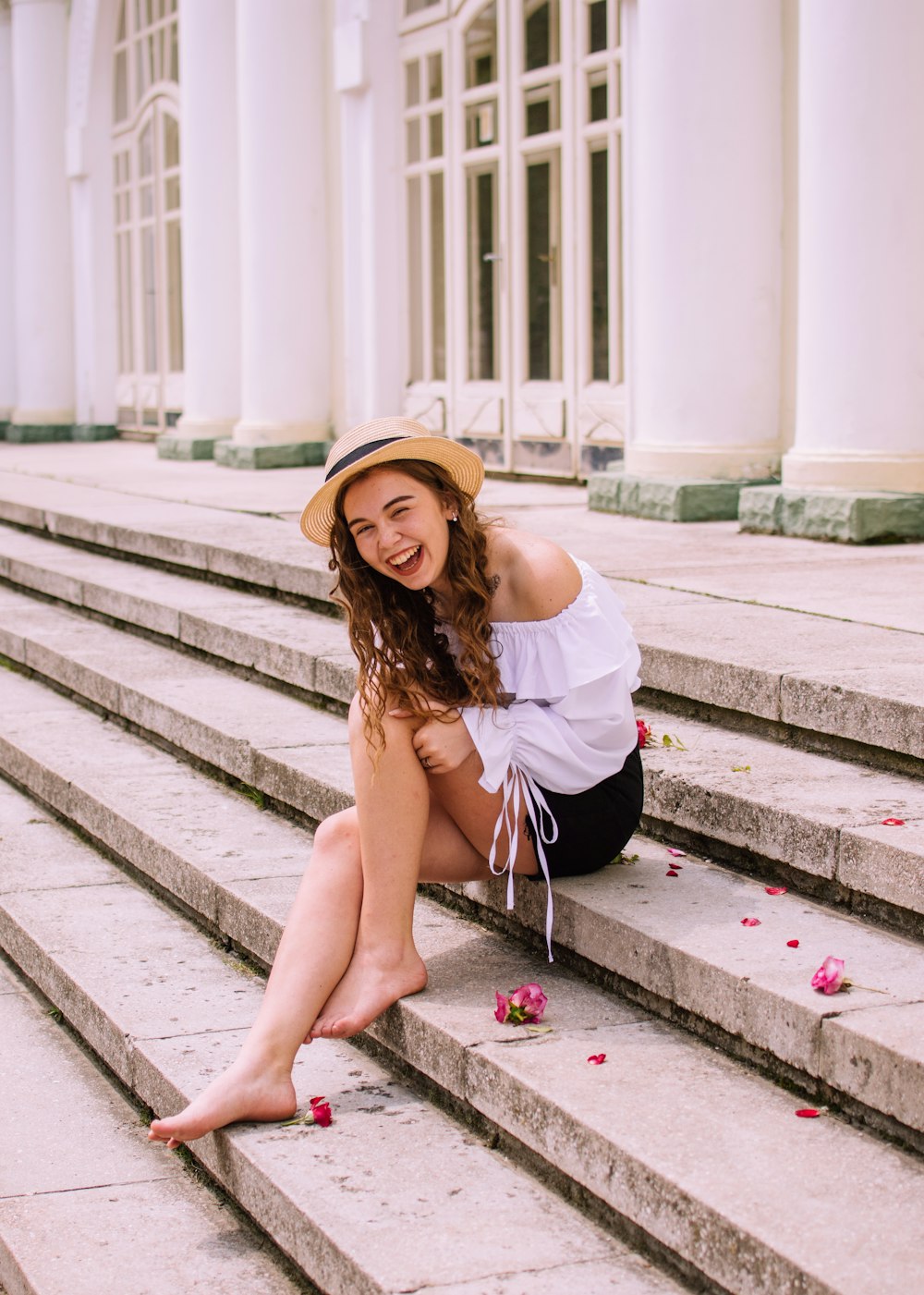 woman in white shirt and black skirt sitting on concrete stairs