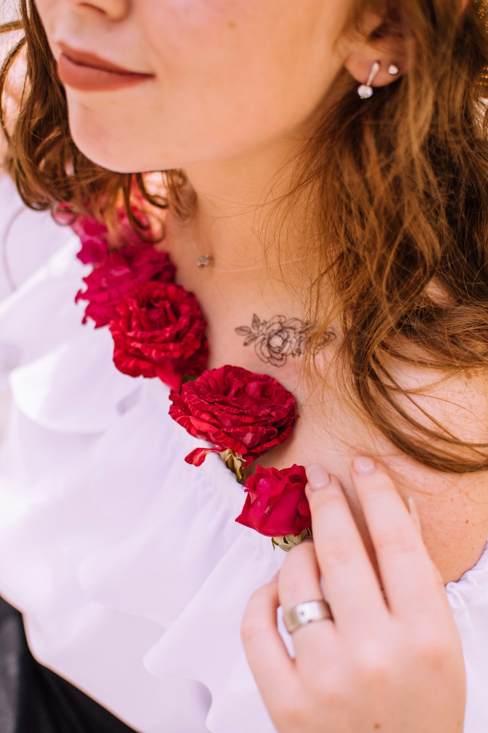 woman in white dress with red rose necklace