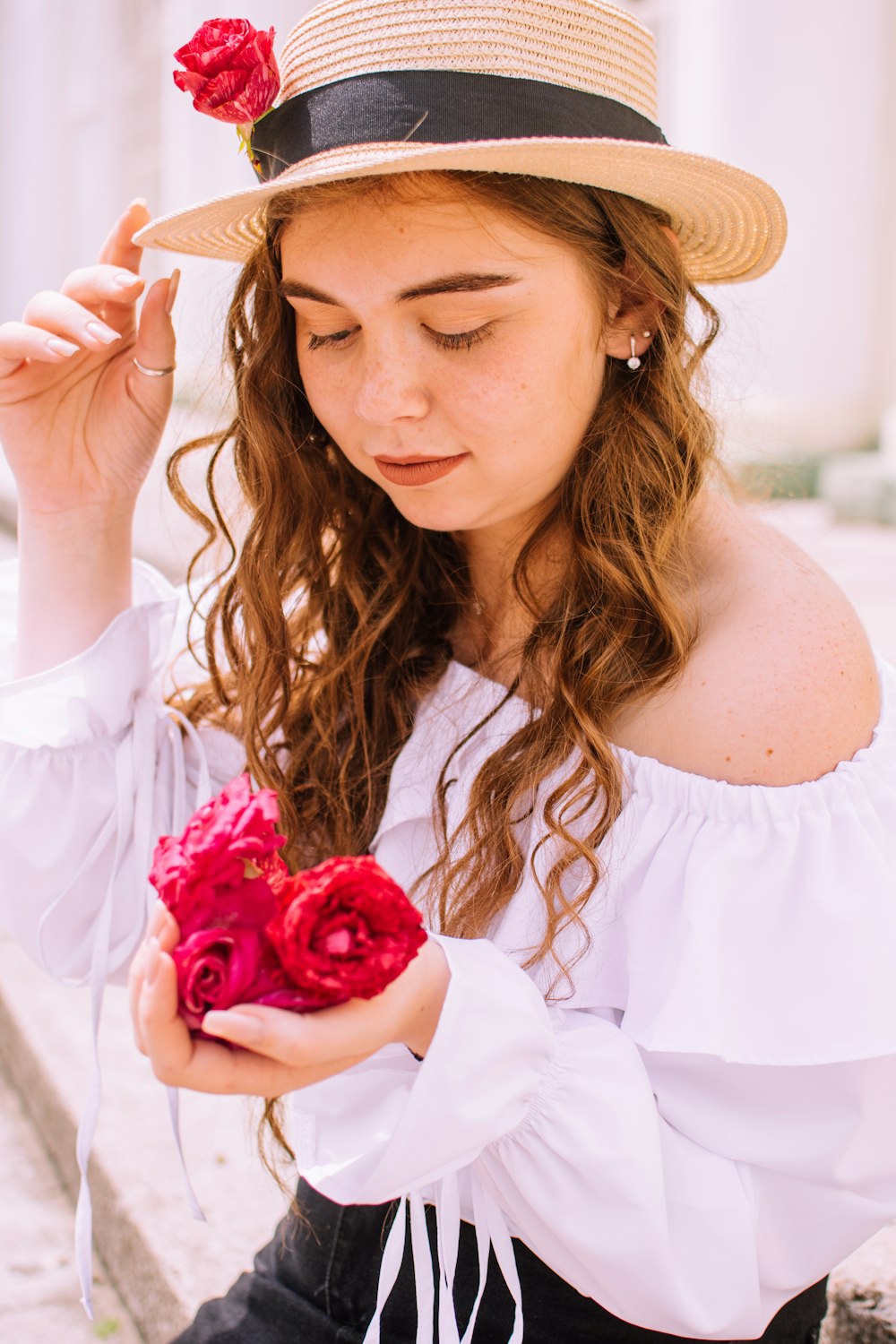 woman in white off shoulder dress holding red rose