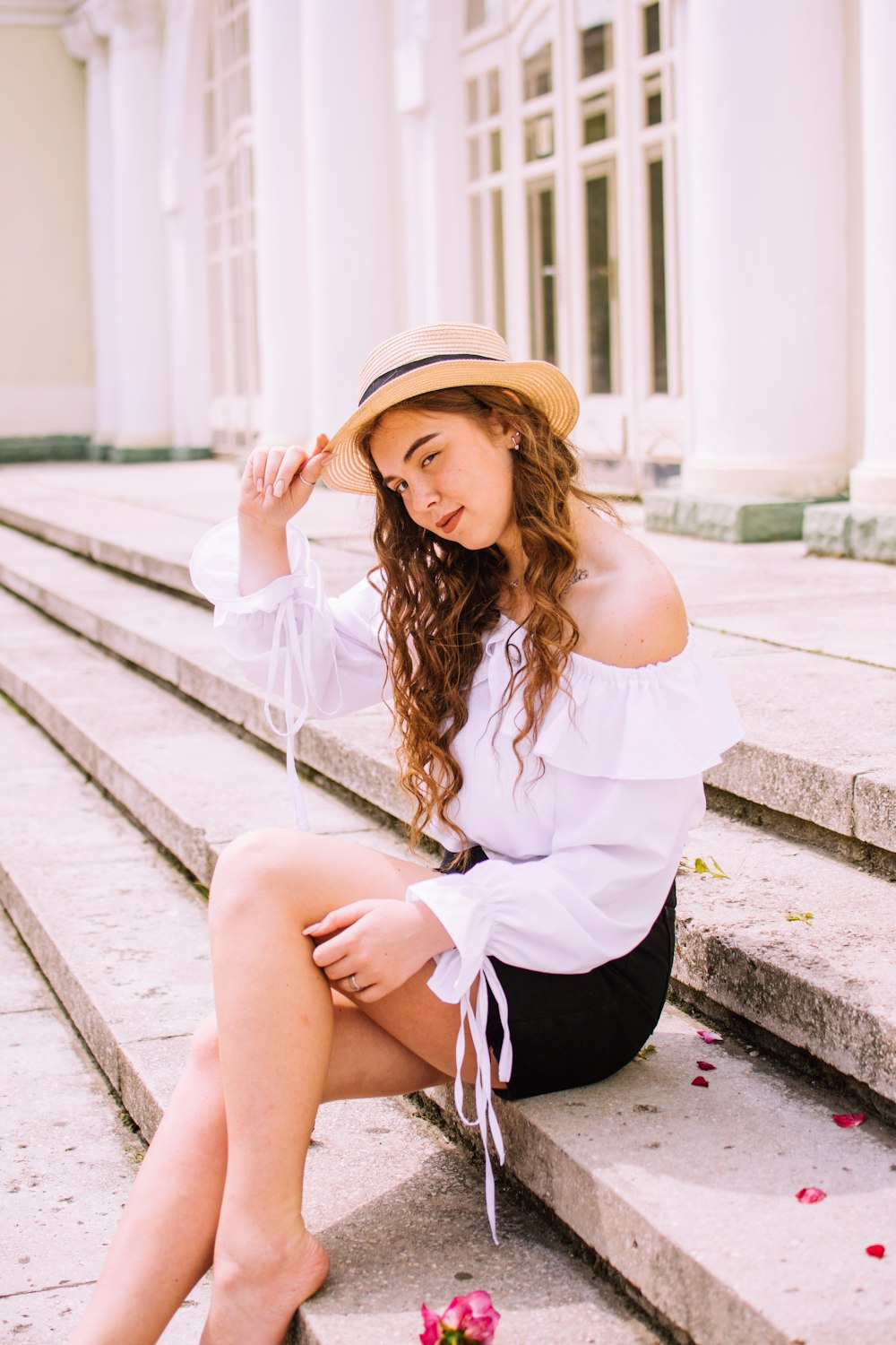 woman in white long sleeve shirt and black skirt sitting on concrete stairs during daytime