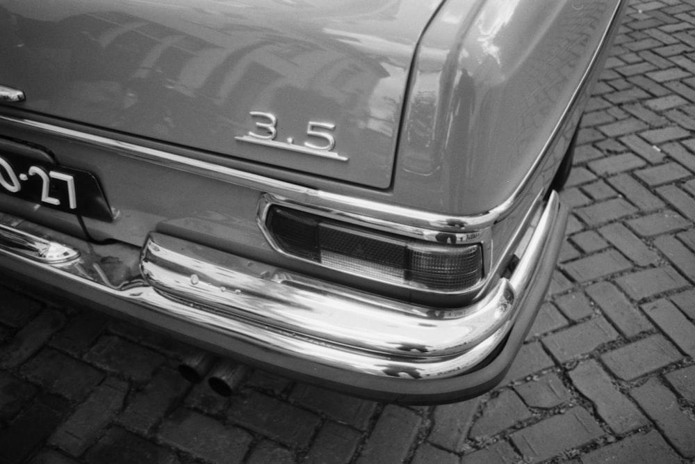 grayscale photo of car on brick pavement