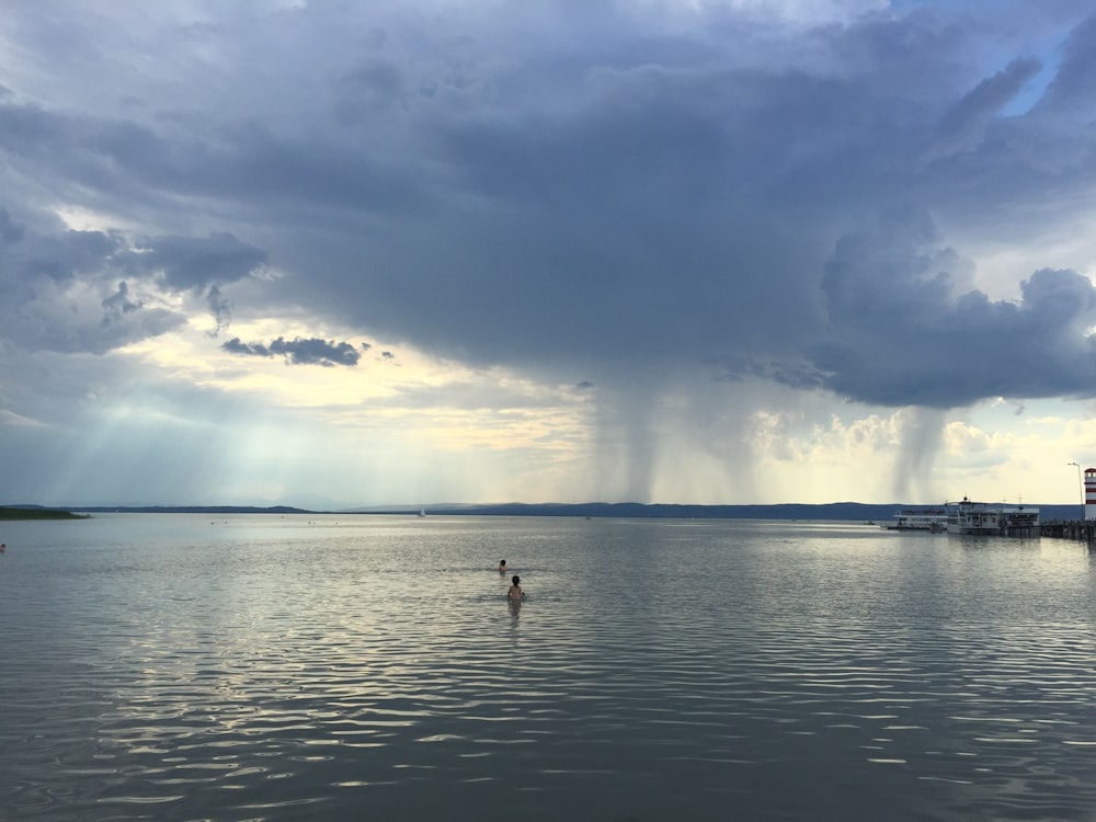 person in water under cloudy sky during daytime