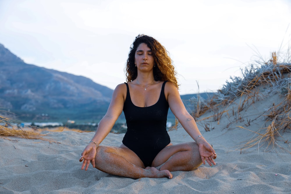 woman in black tank top sitting on gray sand during daytime