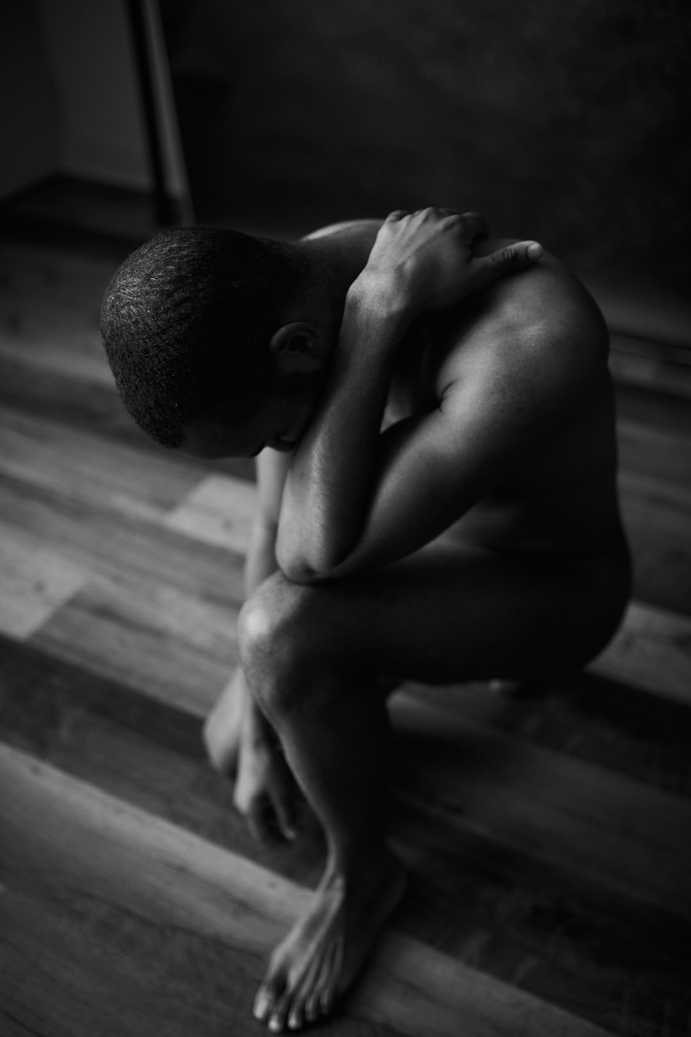 topless man sitting on wooden floor