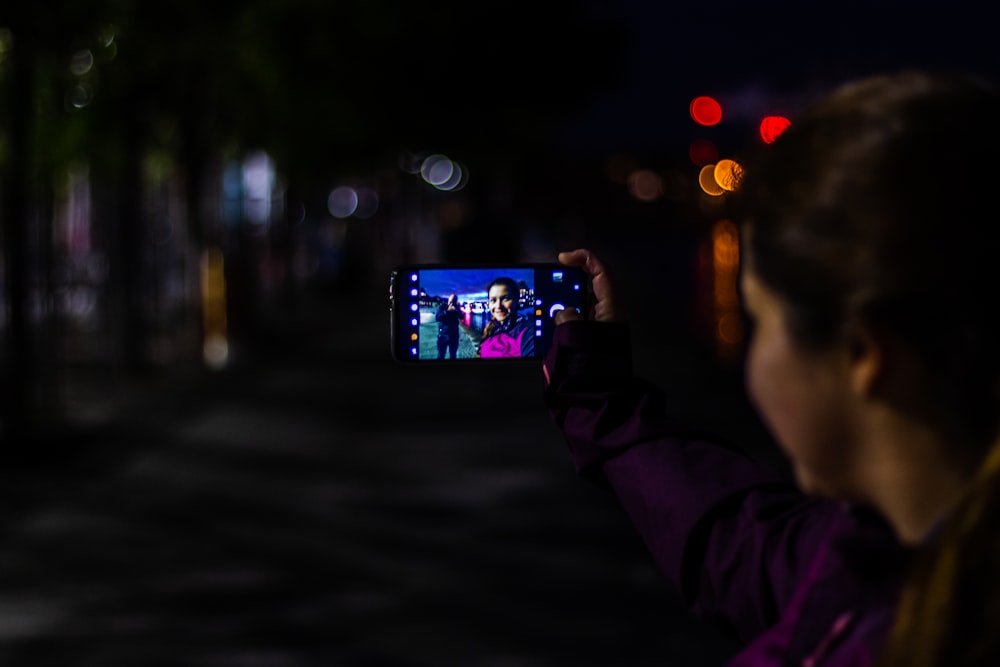person holding smartphone taking photo of city during night time