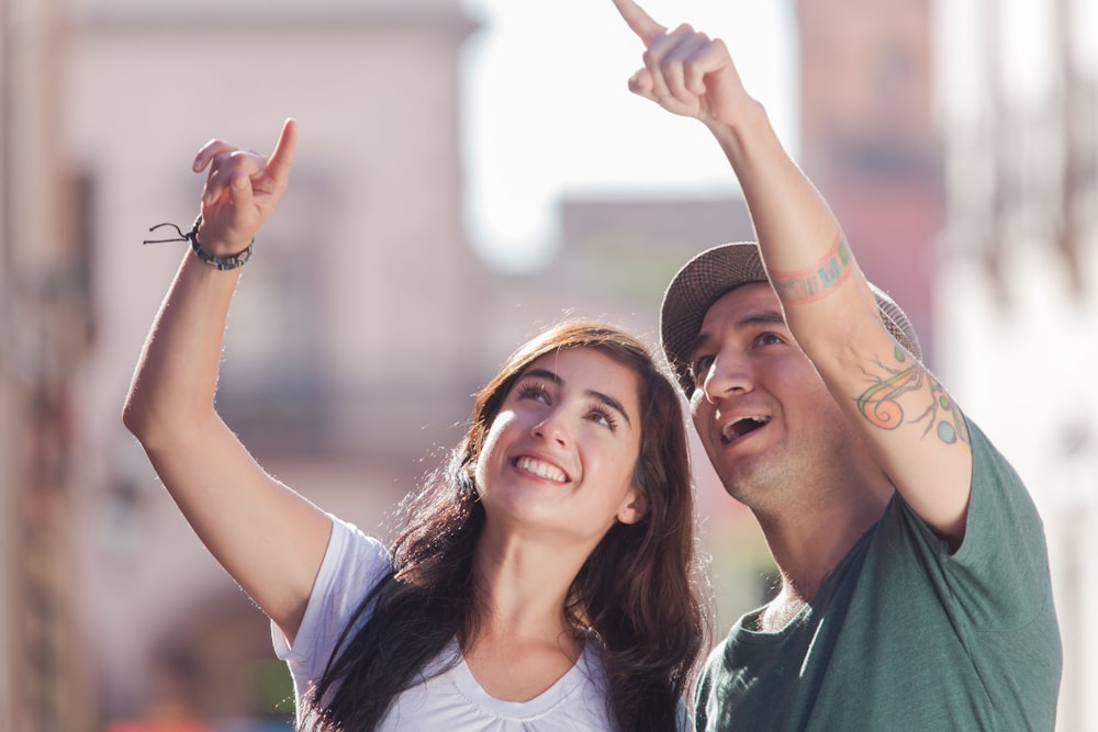 woman in white tank top smiling beside man in green crew neck shirt