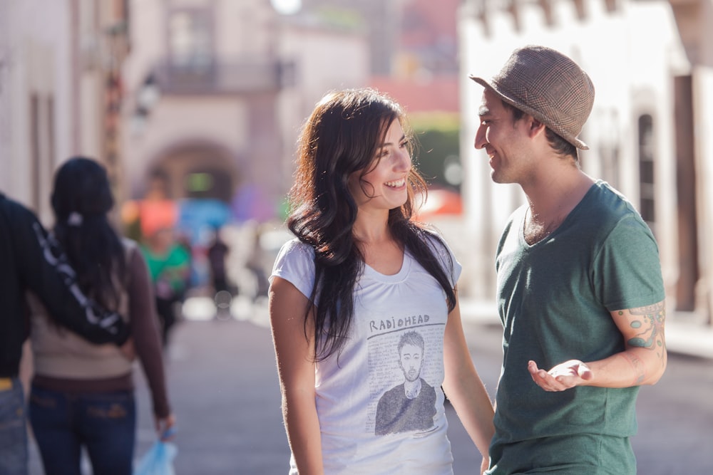 Femme en T-shirt à col rond gris et chapeau fedora gris debout à côté d’une femme en gris