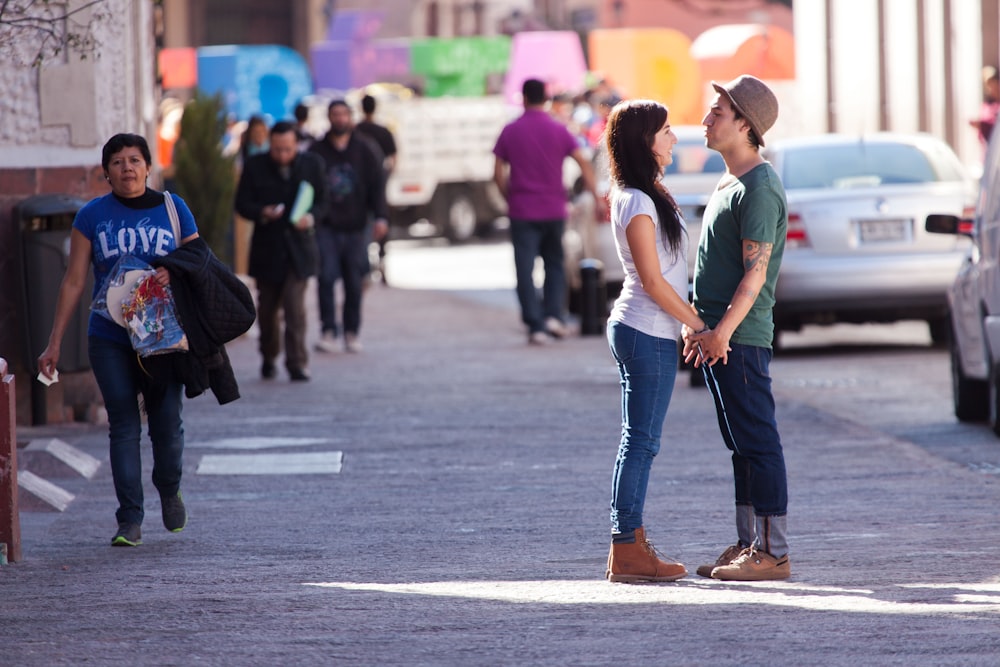 man in green t-shirt and blue denim jeans walking on street during daytime