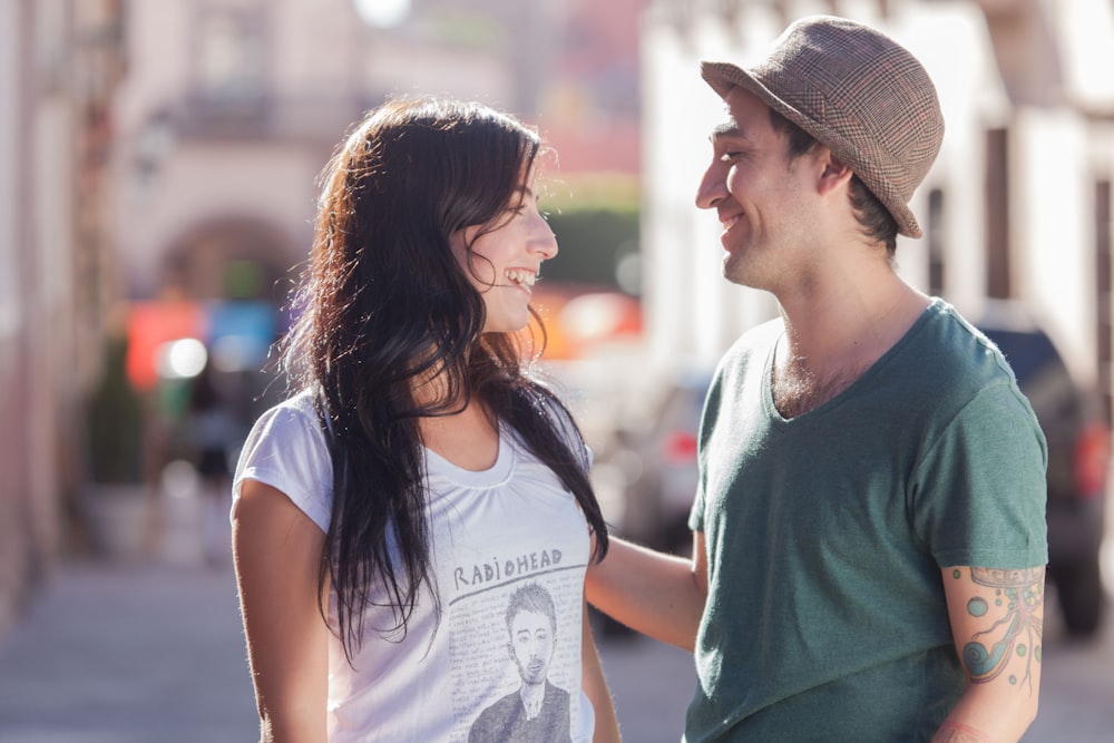 man in green crew neck t-shirt kissing woman in white t-shirt during daytime