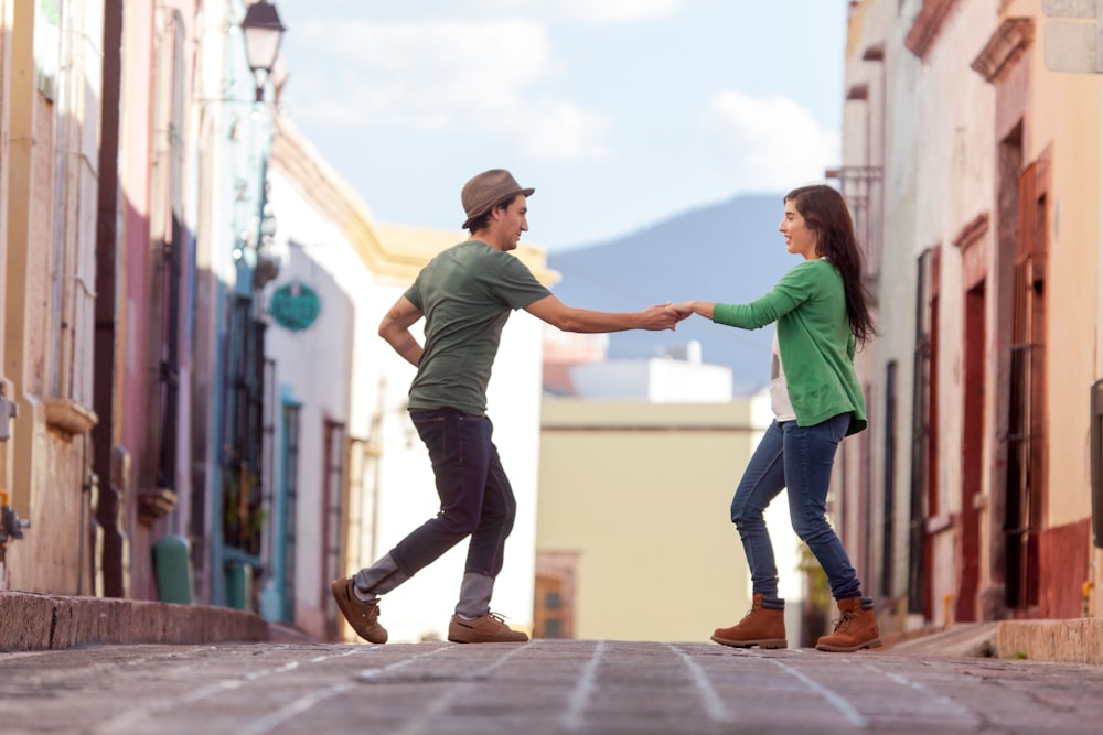 man in green t-shirt and woman in green t-shirt walking on gray concrete pavement