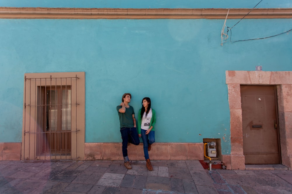 woman in black jacket standing beside blue painted wall