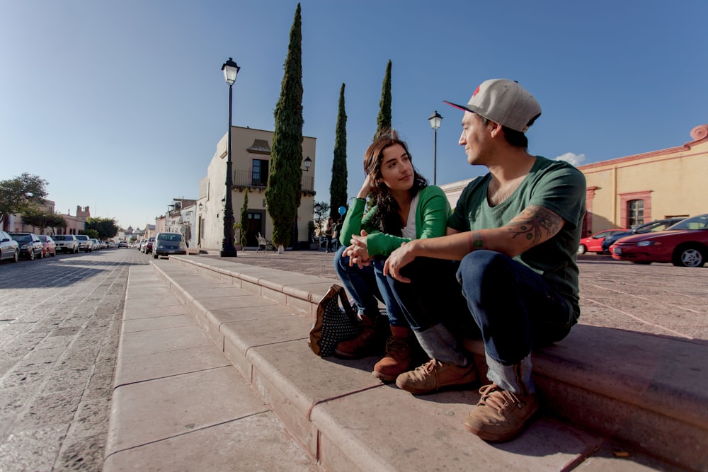 man in green crew neck t-shirt sitting on concrete bench during daytime