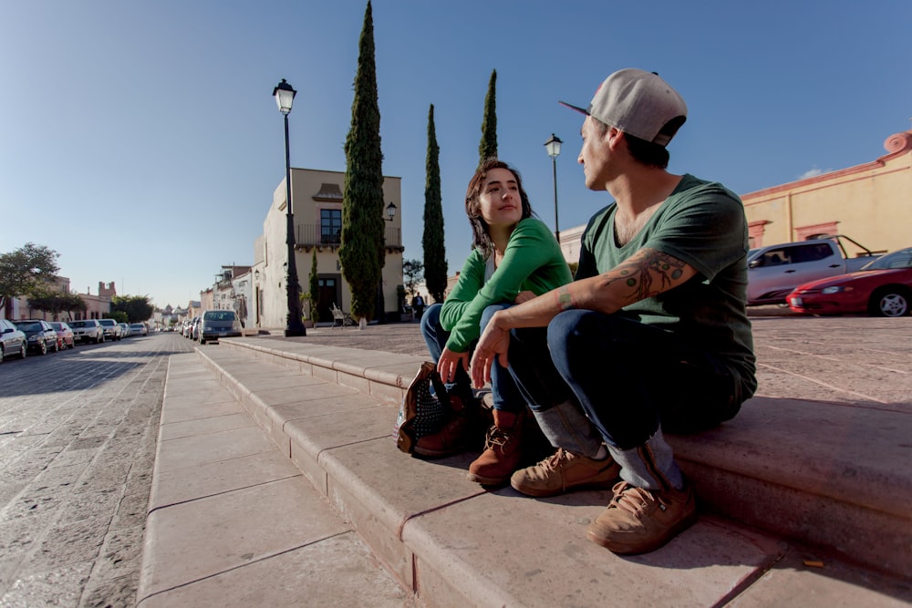 man in green shirt and black pants sitting on concrete bench during daytime